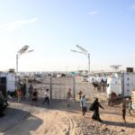 People Walk At The Gate Of A Makeshift Camp For Displaced People Near Aden