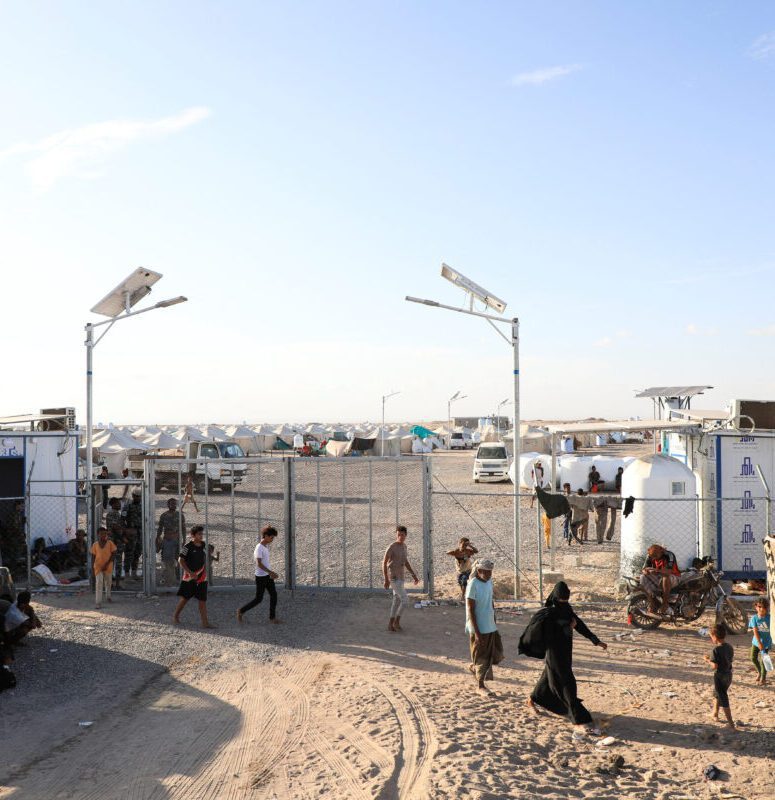 People Walk At The Gate Of A Makeshift Camp For Displaced People Near Aden